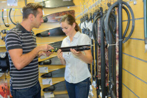 Employee helping customer review merchandise in a dive shop aisle.